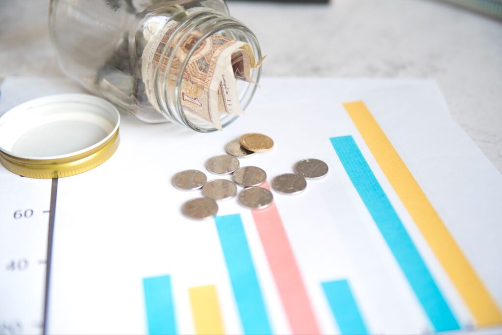 Close up of coins and jar on paper with statistics